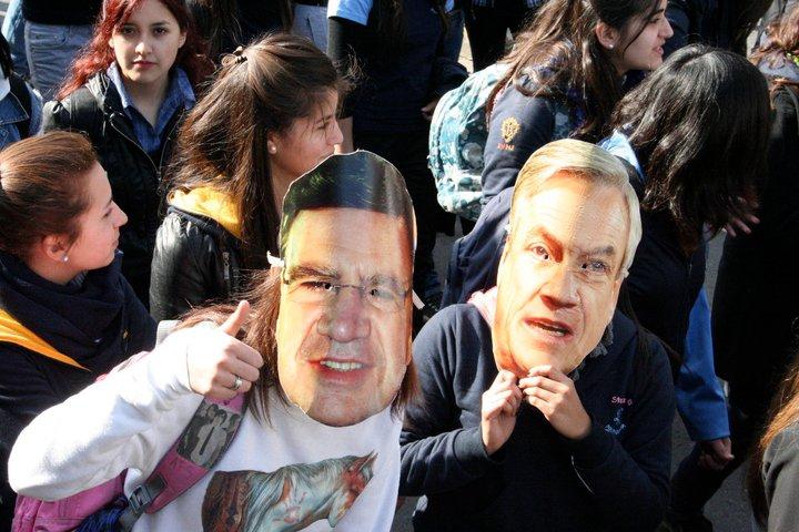 Demonstranten mit Masken: links  Bildungsminister Lavin, rechts Präsident Piñera
