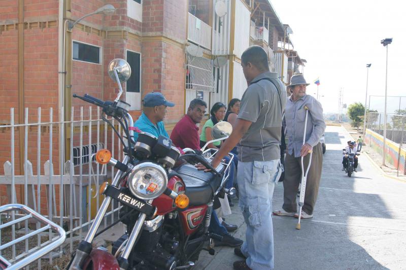 Wählerinnen und Wähler warten nach der Stimmabgabe in Ciudad Caribia mit ihren Nachbarn auf der Straße
