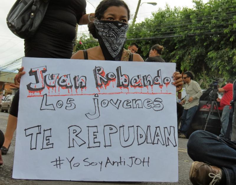 Studentin mit Plakat "Juan du stiehlst - die Jugend lehnt dich ab"
