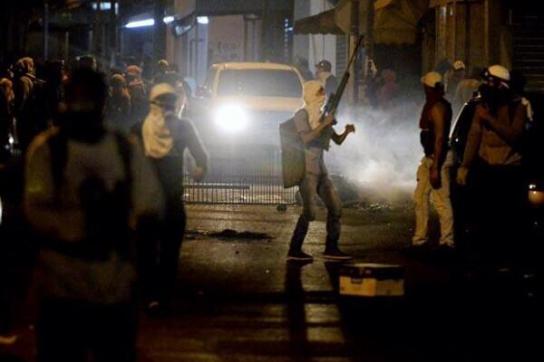 Vermummter oppositioneller Aktivist mit einem Gewehr bewaffnet bei Auseinandersetzungen mit der Polizei im Hauptstadtbezirk Chacao